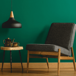 integrating your values: chair and side table with hanging light against a dark green wall